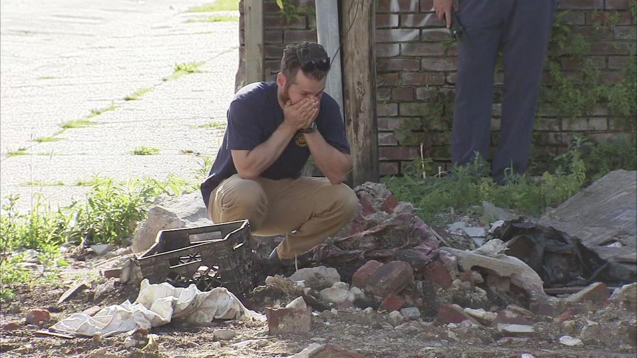  A man kneels next to a pile of rubble and debris, with his head in his hands, as police investigate the discovery of human remains in South Wales.